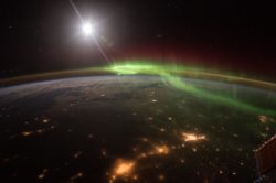Earth at night highlighting the green and red hues of an Aurora